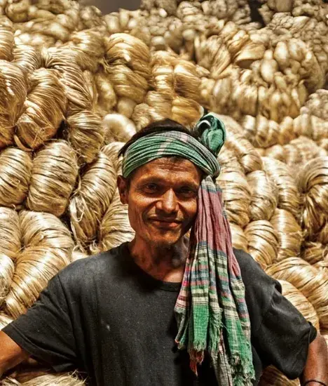 Worker with raw jute fiber bundles in warehouse